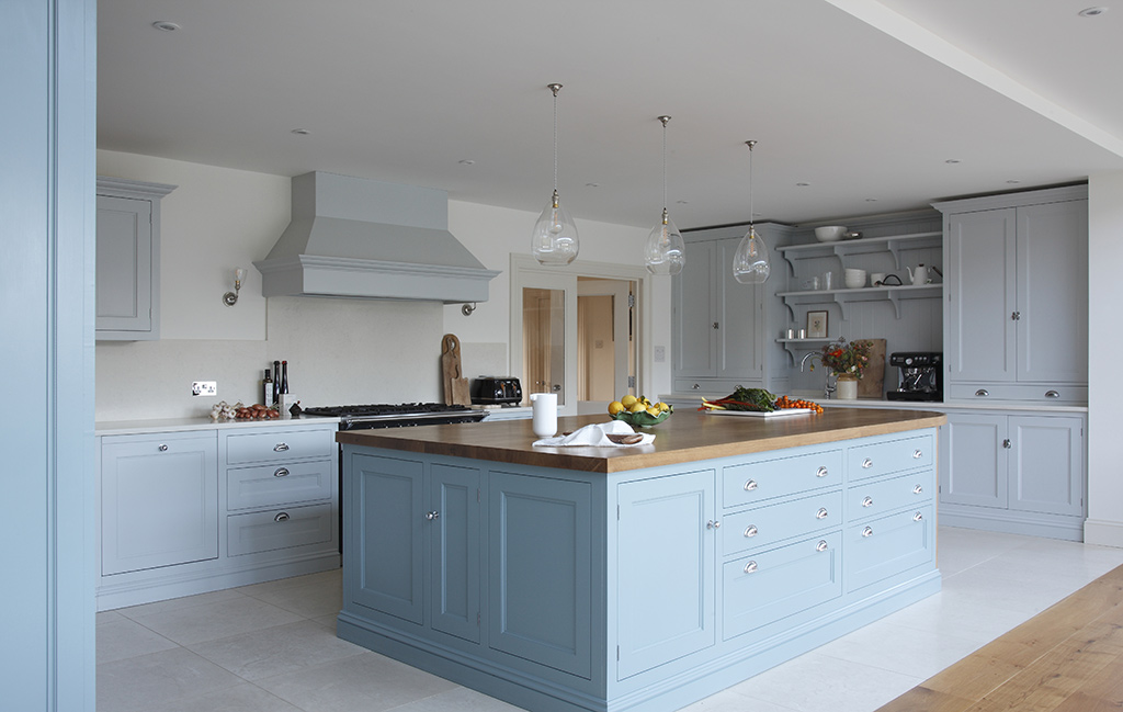 Spacious pastel kitchen with three glass pendant lights suspended over a kitchen island creating a welcoming space.