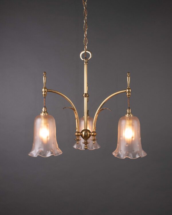 A 3 branch antique Edwardian chandelier, with 3 fluted rim satin glass shades. Photographed in a dark studio to capture the glowing light