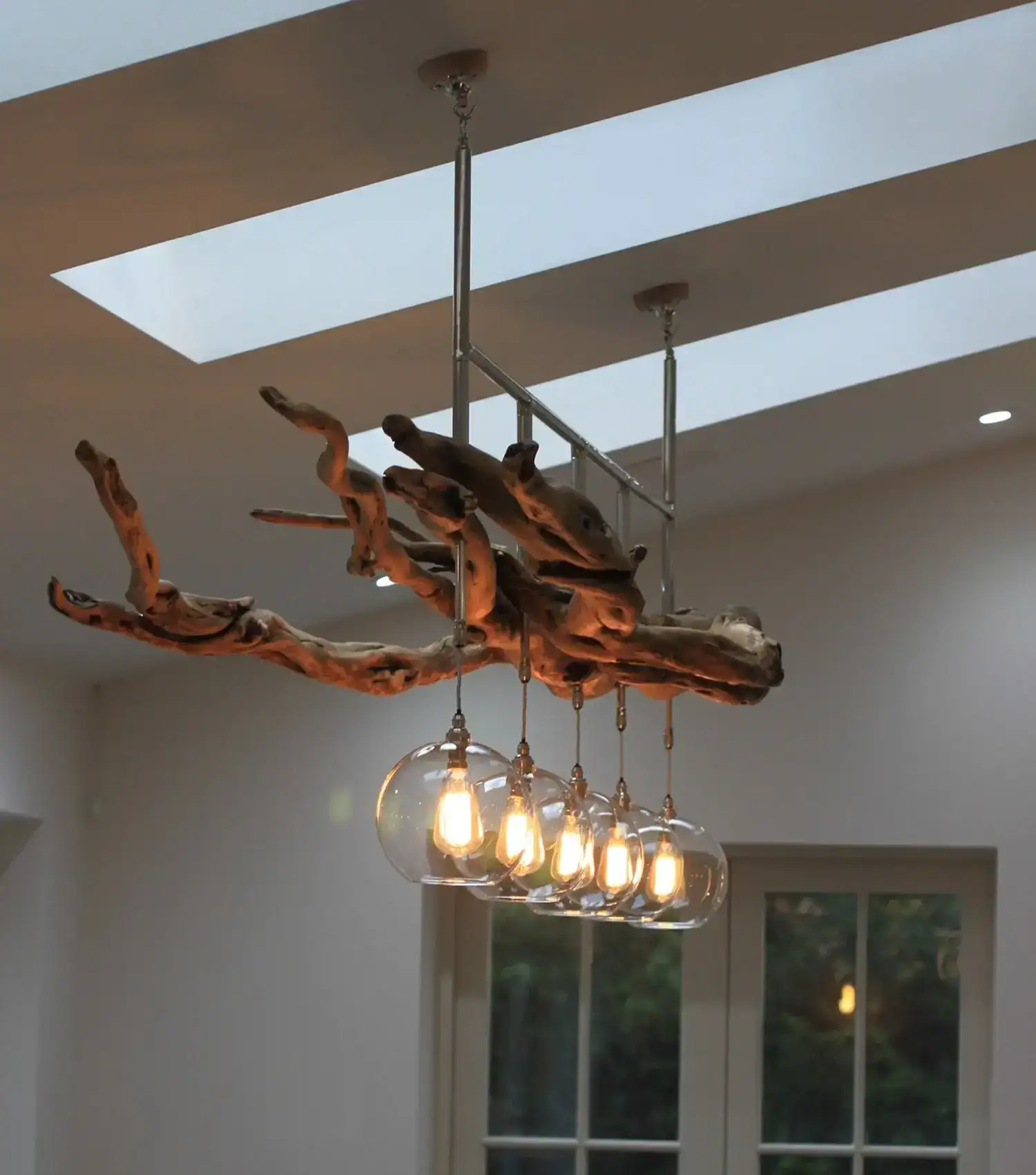 Modern driftwood chandelier with glass bulb pendant lighting in a contemporary interior.