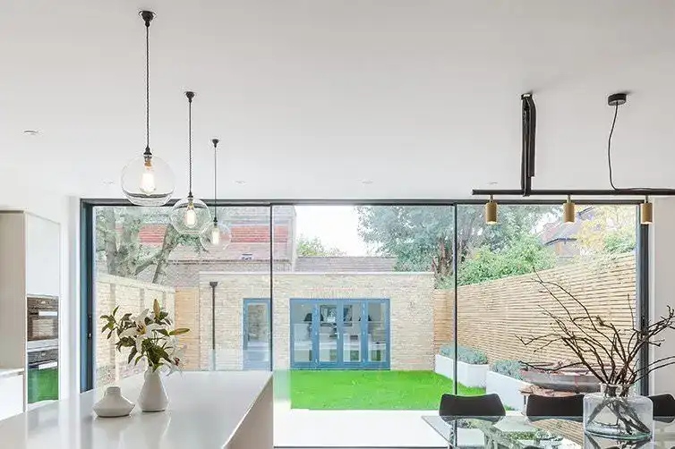 Bright modern kitchen featuring large glass windows and stylish pendant lights.
