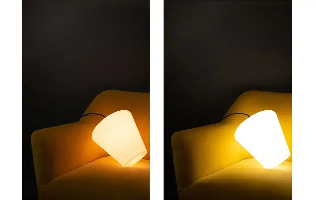 Soft yellow bedside lamp illuminating a modern bedroom setting with a dark background.