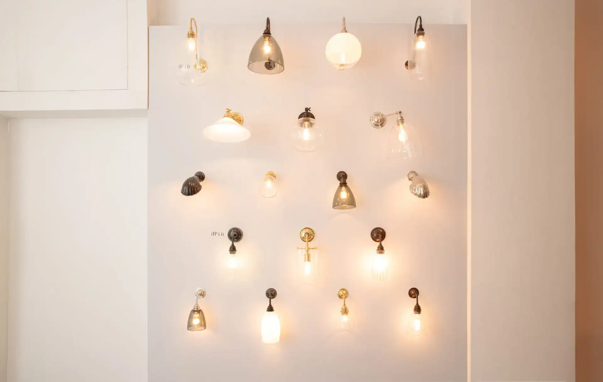 Modern wall-mounted lighting fixtures with various styles and finishes on a white wall.
