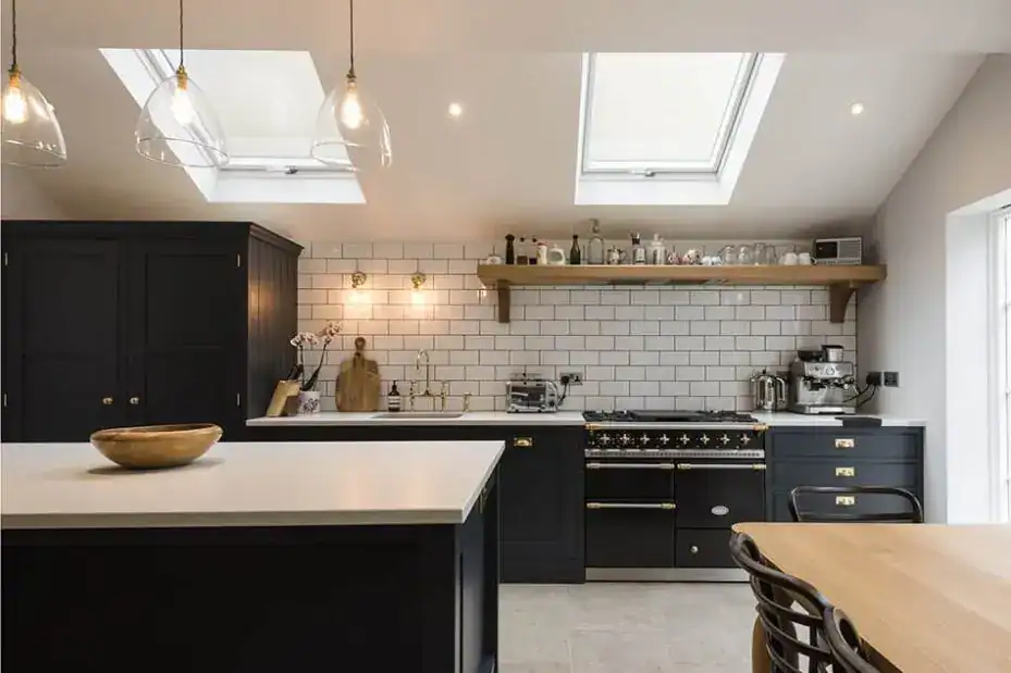 Modern kitchen with black cabinets, white subway tiles, and skylights for natural light.