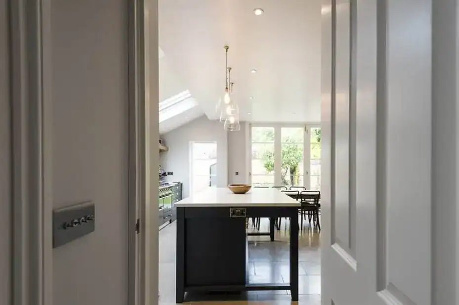 Bright modern kitchen with pendant lights and large windows, open-plan design.