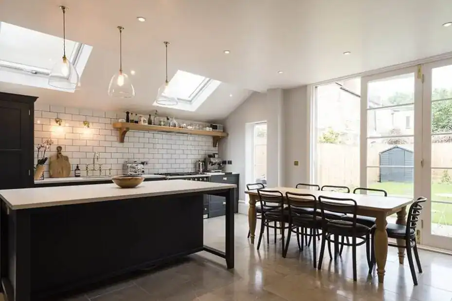 Modern kitchen with Fritz Fryer lighting, white brick backsplash, and large windows for natural ligh.