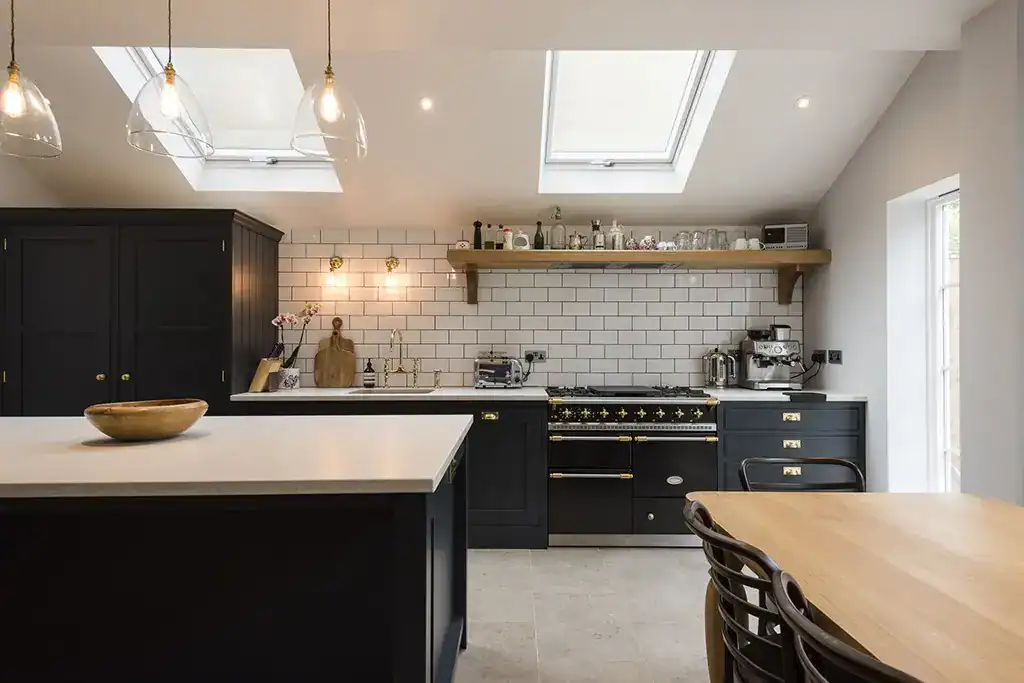 Bright kitchen featuring black cabinets, white subway tiles, and natural light from skylights.