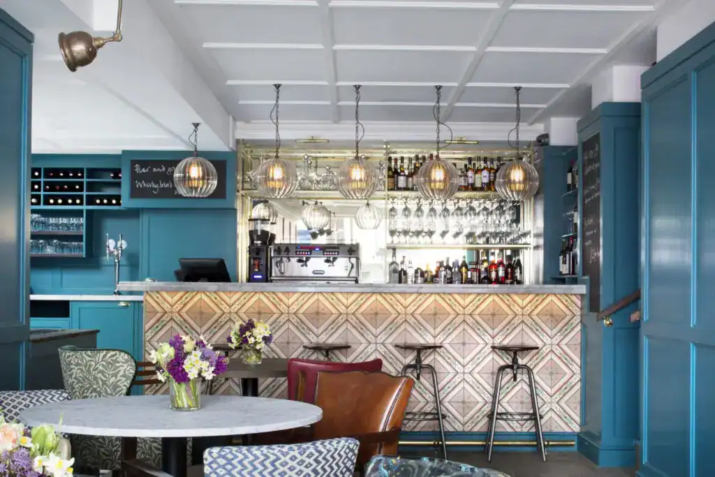 Modern blue bar area with hanging pendant lights and floral table centrepiece.