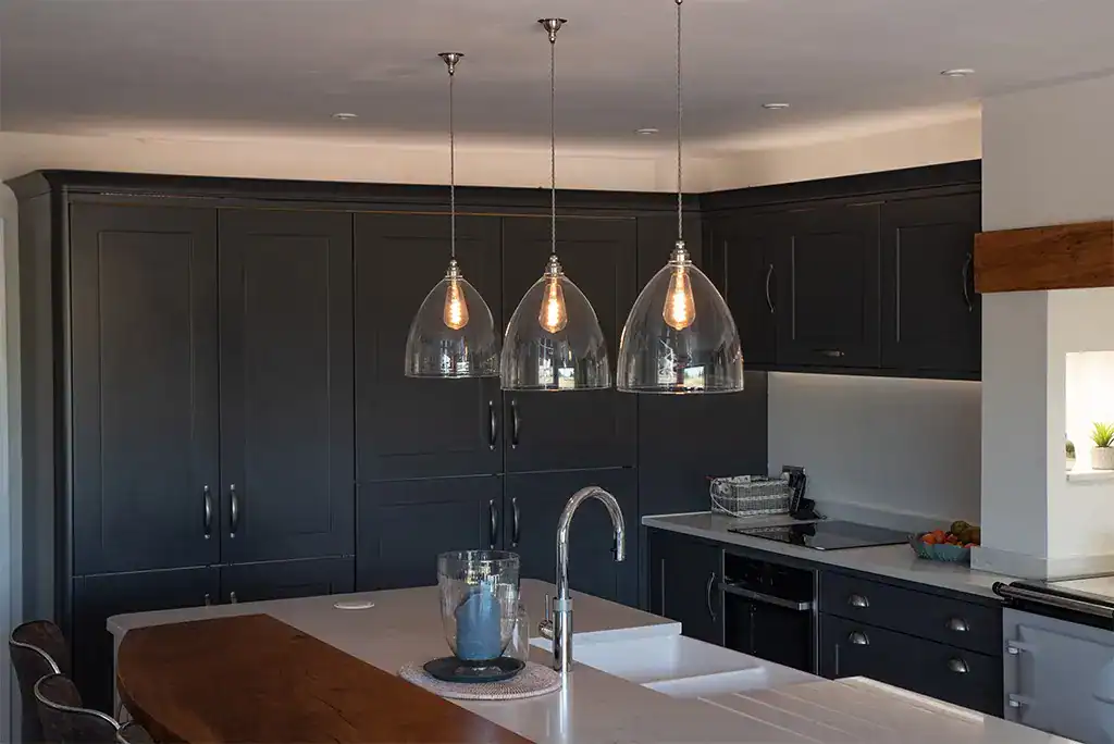 Stylish black kitchen with three pendant lights hanging above the island.