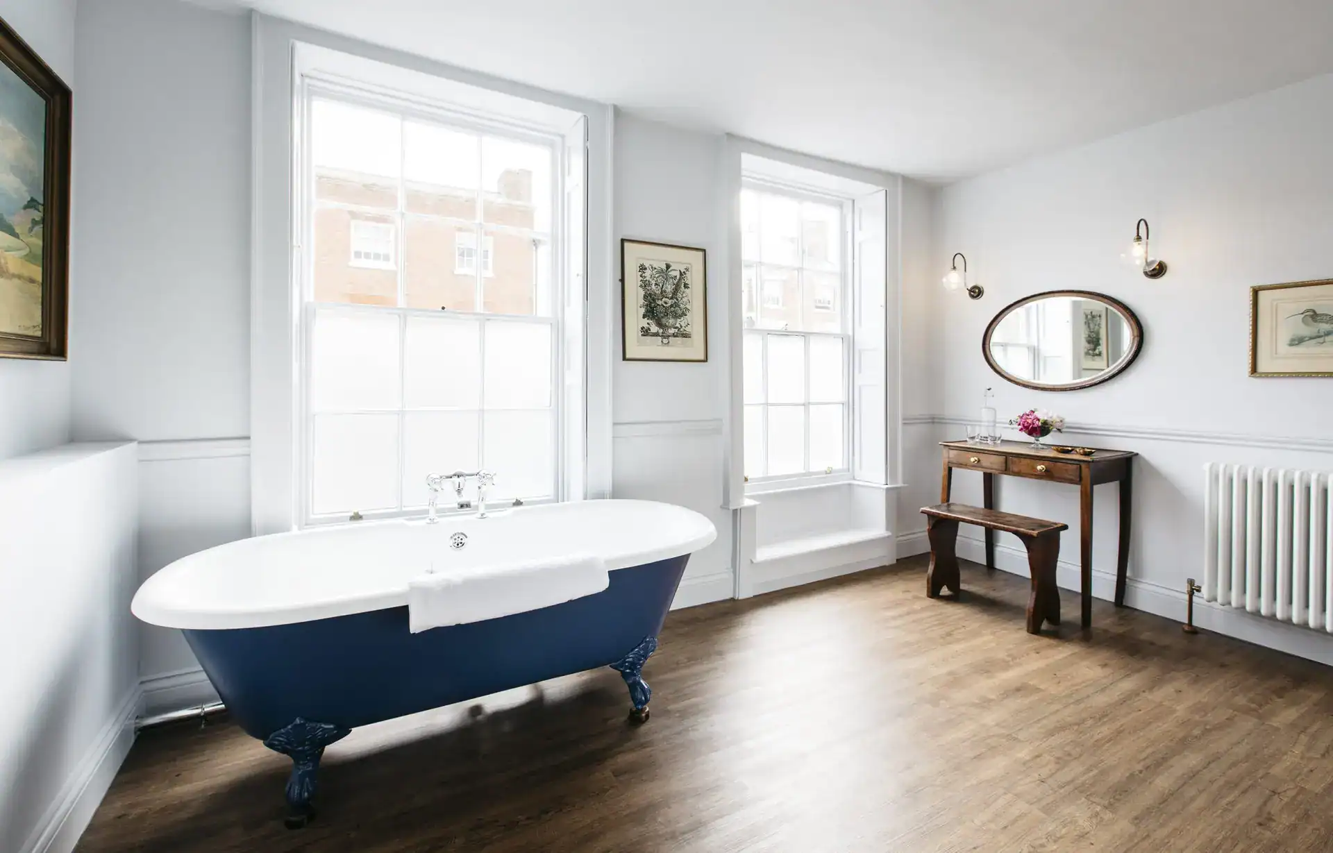 Elegant freestanding bathtub in a bright, modern bathroom with large windows and stylish decor.