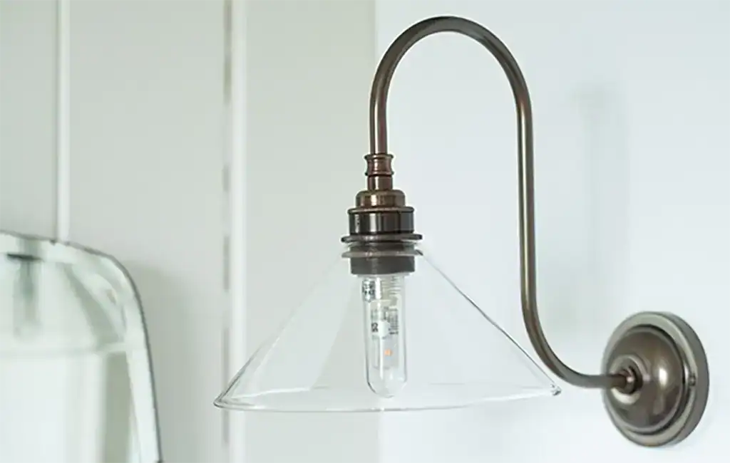 Wall-mounted industrial-style wall light with glass shade.
