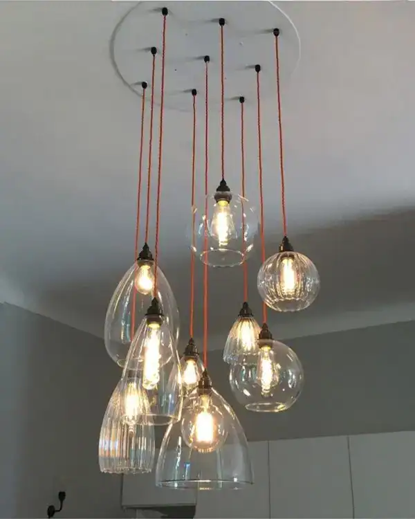 Pendant light fixture with multiple glass globes and exposed bulbs.