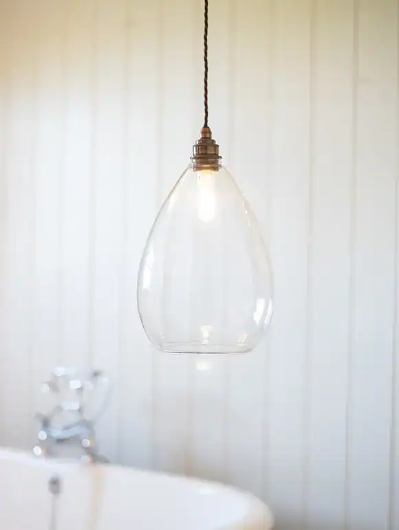Pendant glass light fixture with exposed bulb.