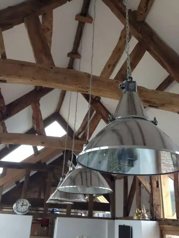 Industrial pendant lights hanging from wooden beams in a rustic interior.