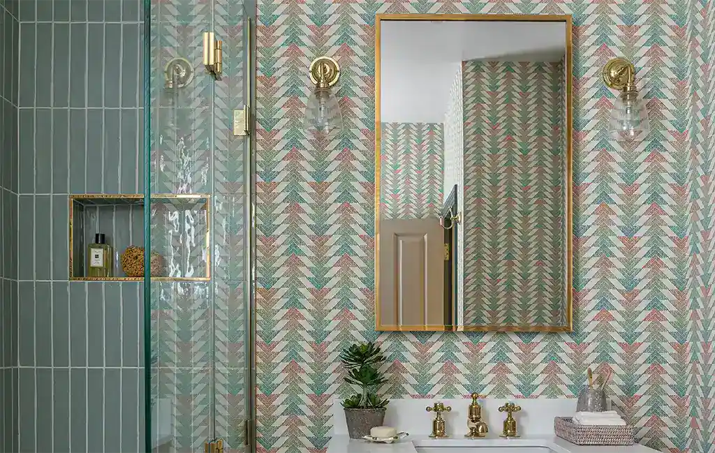 Elegant bathroom lighting with gold fixtures and patterned wallpaper.