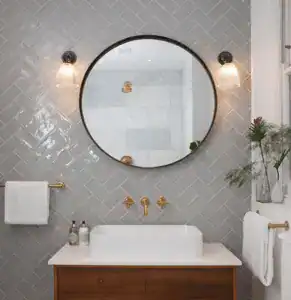 Bathroom wall lighting with round mirror and grey tiled wall.