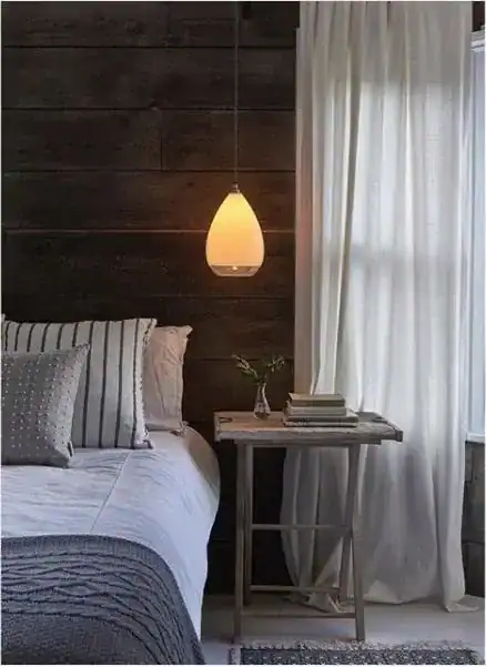 Pendant light over bedroom with wooden wall background.