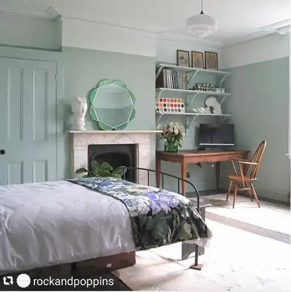 Soft pastel bedroom with a fireplace, decorative mirror, and workspace featuring shelves and a woode.