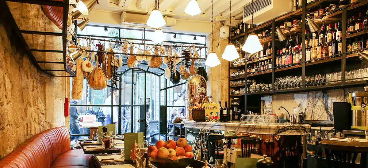 Interior of a café with hanging decorations, warm lighting, and shelves stocked with bottles and gla.