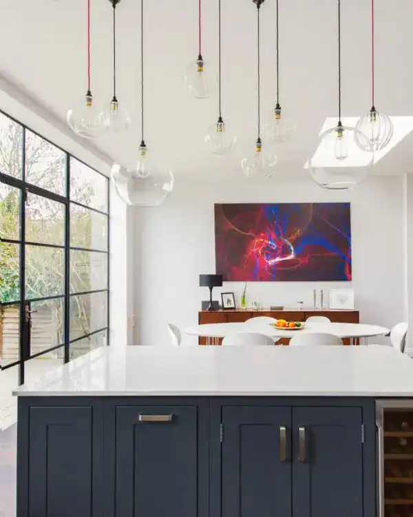Modern pendant lighting in a bright, contemporary kitchen with large windows and colourful artwork.