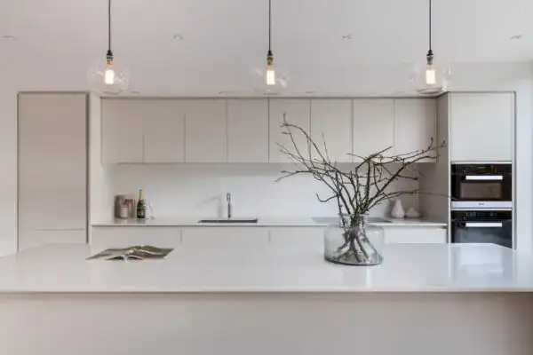 Modern minimalist kitchen with pendant lighting and a decorative branch arrangement on the island.