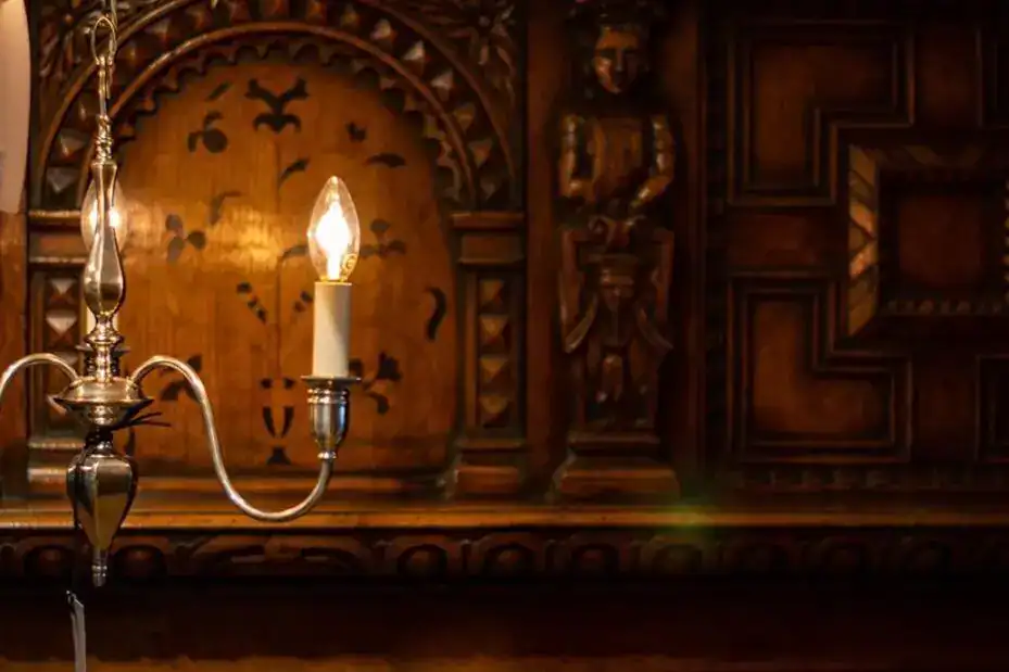 Vintage wall sconce with candle-style bulb illuminating a traditional wooden interior.