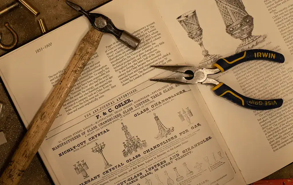 Antique glassware and vintage tools displayed on open book pages.