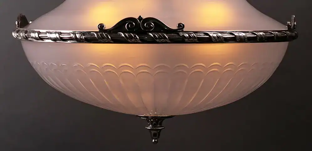 Vintage ceiling light fixture with ornate metal accents and frosted glass shade.