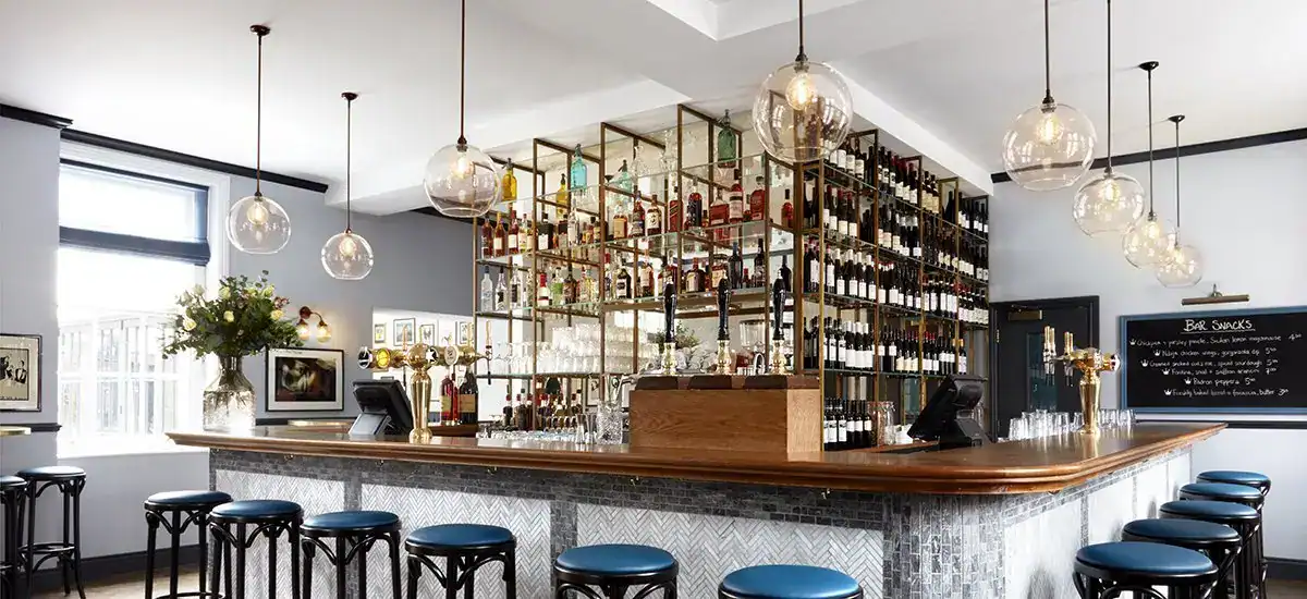 Contemporary bar interior featuring pendant lighting and extensive wine storage.