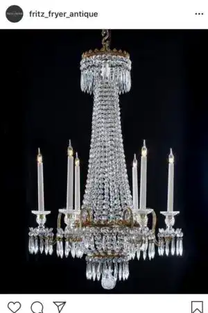 Elegant crystal chandelier with multiple candle-style lights, hanging against a dark background.