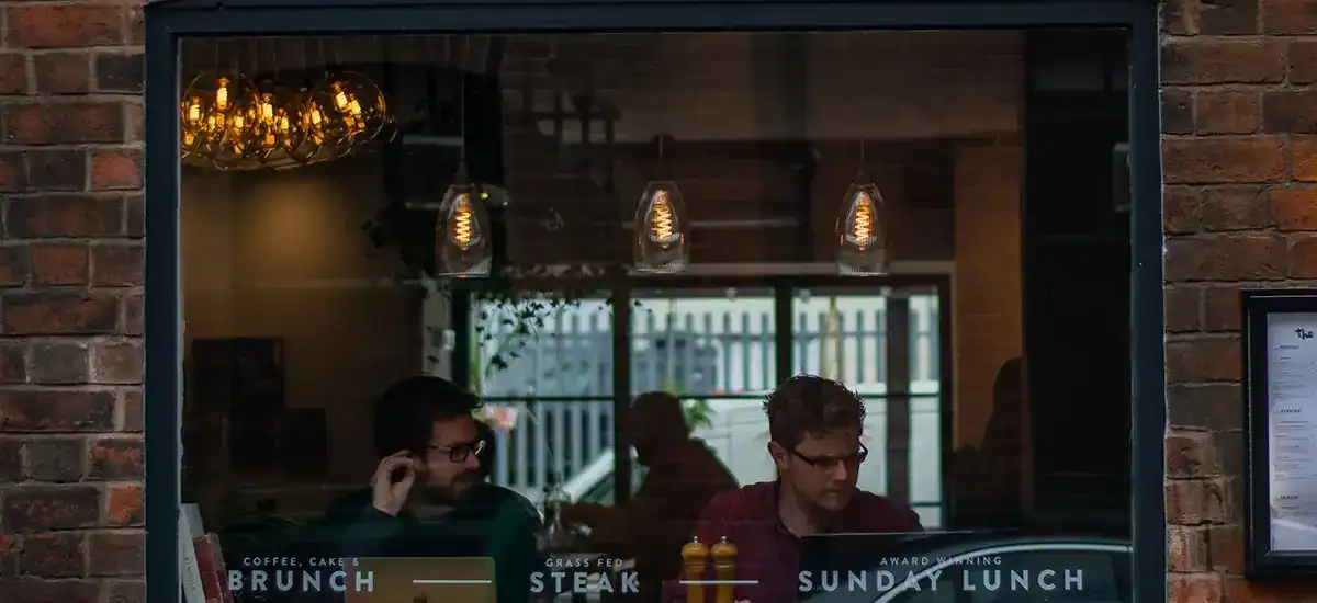 Industrial pendant lights illuminating a café interior with brick walls.