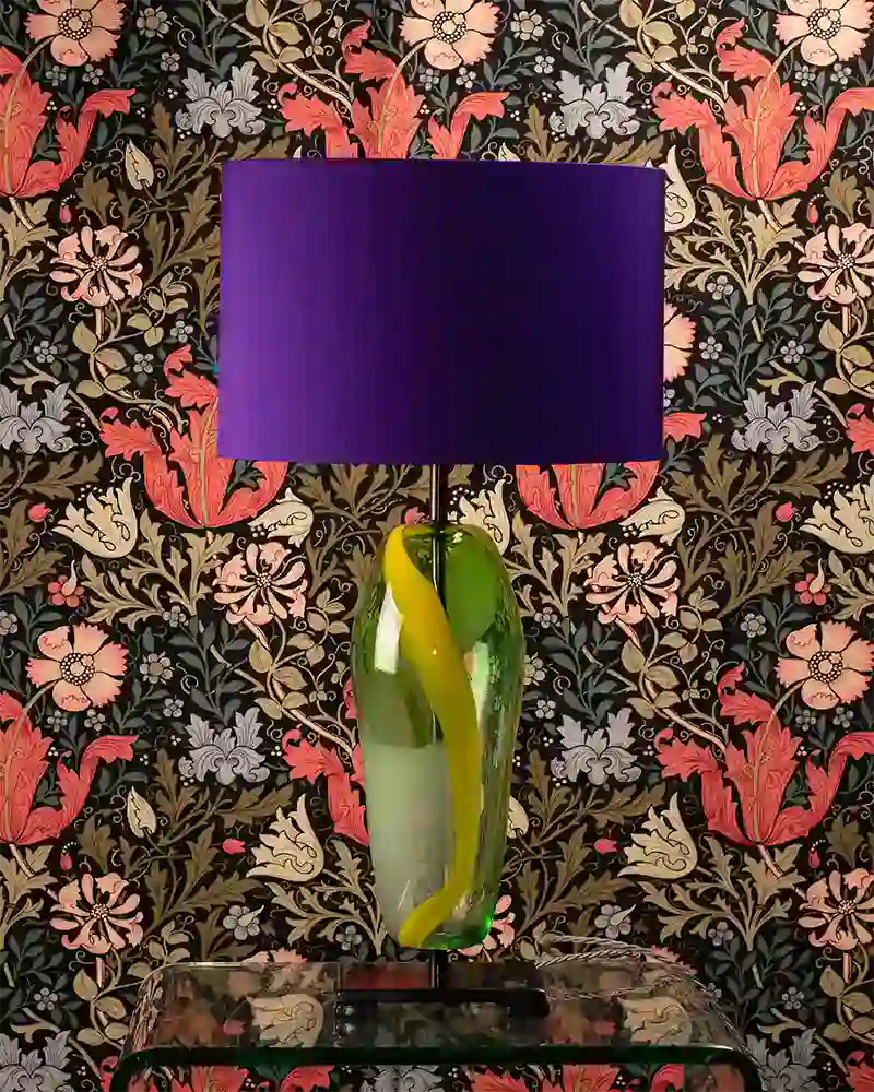 Elegant table lamp with a vibrant purple lampshade and a decorative glass base, perfect for enhancin.