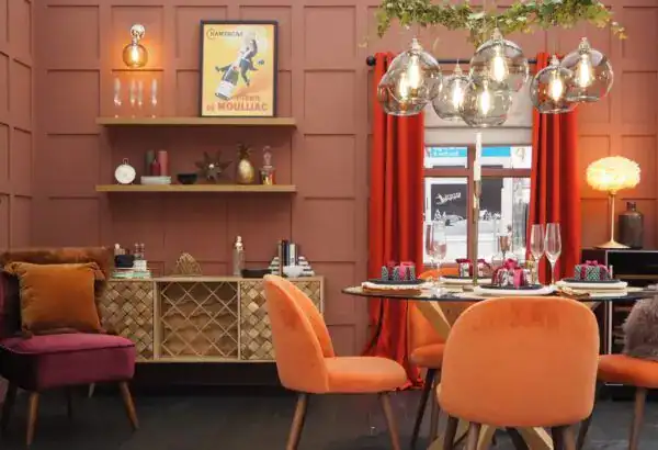 Contemporary dining area featuring stylish pendant lights, colourful chairs, and warm-toned walls cr.