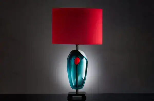 Modern glass table lamp with red lampshade and sleek design.