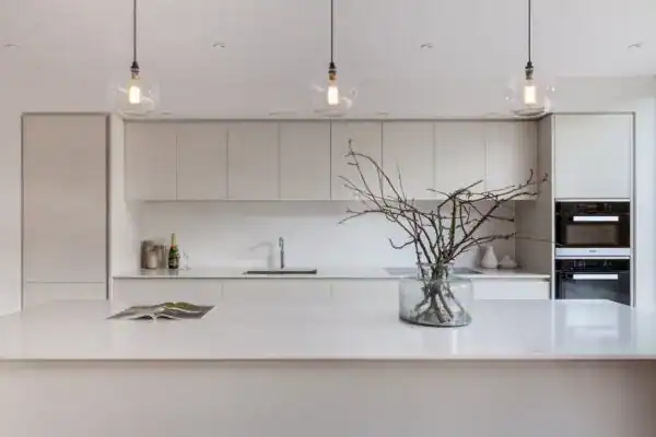 Modern minimalist kitchen with pendant lighting and a decorative branch centerpiece.