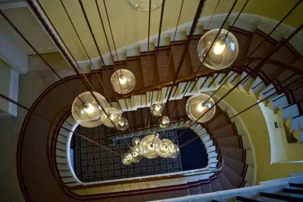 Elegant modern chandelier with multiple glass globes hanging over a spiral staircase.