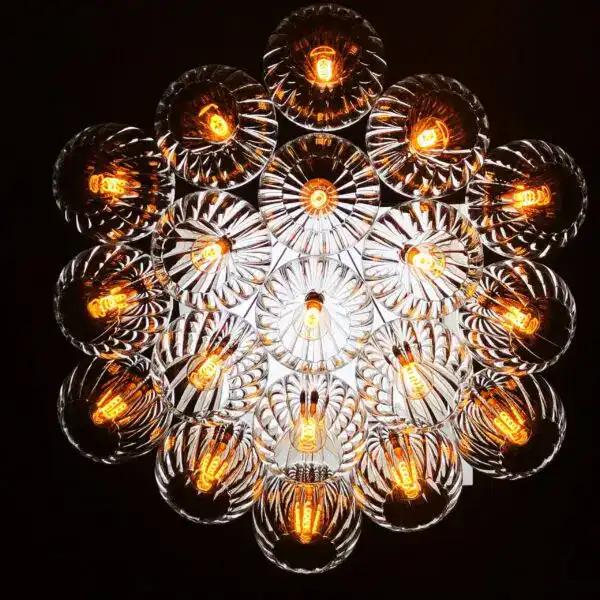 Edison-style filament bulbs in a modern glass chandelier, illuminated against a dark background.