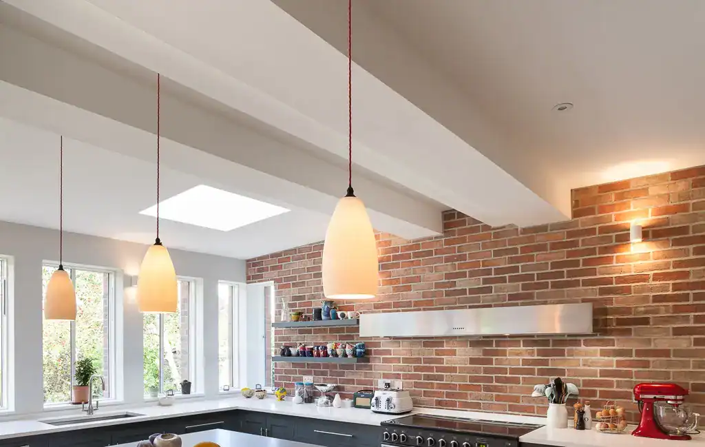 Pendant lighting over kitchen counter with brick wall backdrop.