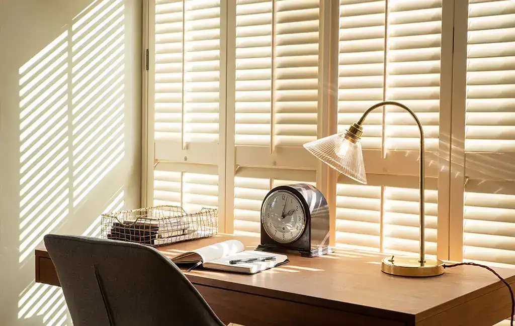 Lighting desk with desk lamp and clock in a bright office.