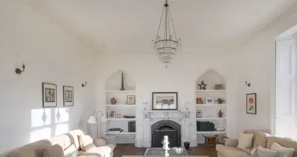 Elegant living room featuring a white fireplace, built-in shelves, and classic decor. Bright, airy s.