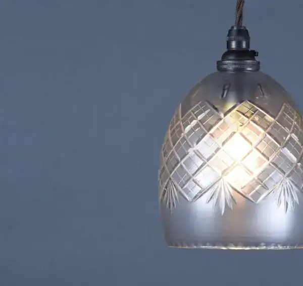 Pendant light with a decorative glass shade and filament bulb.
