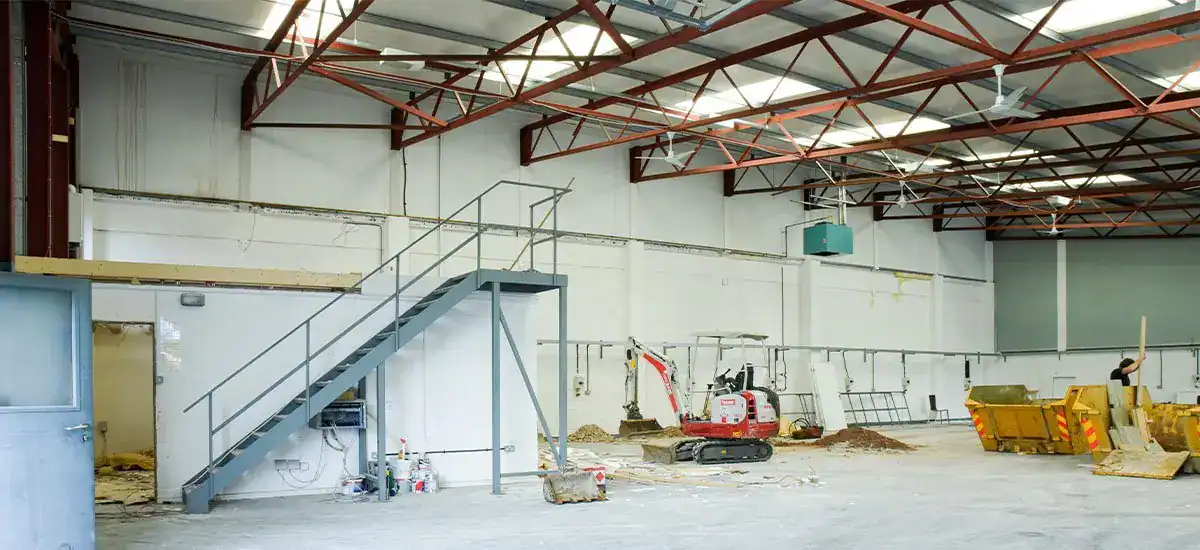 Industrial warehouse interior with lighting and construction equipment.