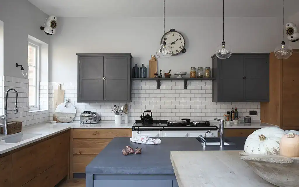 Modern kitchen with grey cabinets, white subway tiles, and a central island featuring a black counte.