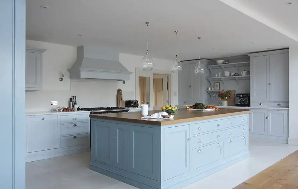 Light-filled kitchen with a central island and pendant lighting, featuring white cabinetry and a con.