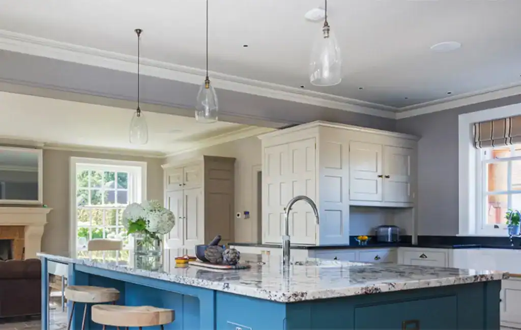 Pendant lights over a kitchen island with marble countertop and blue base.