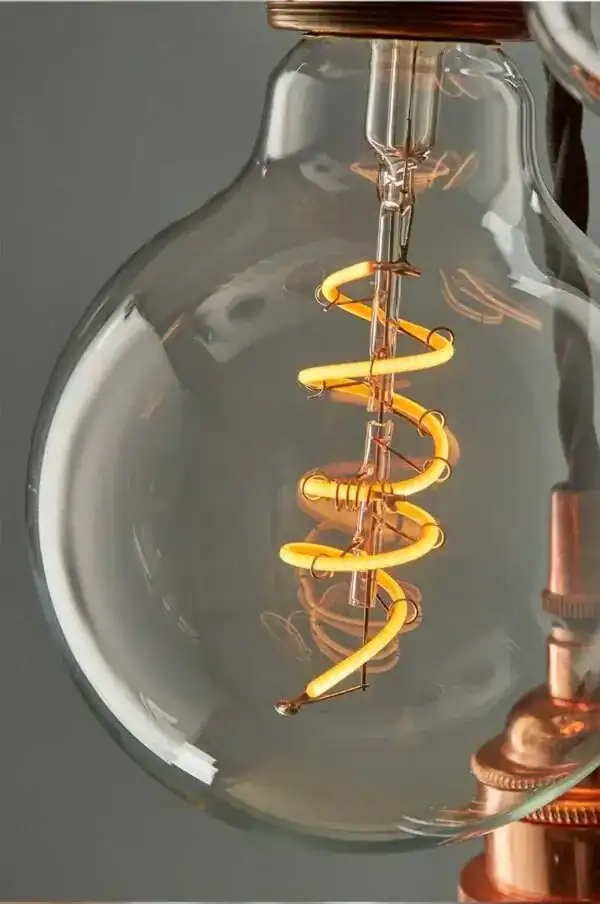 Vintage filament light bulb with exposed filament and copper fittings.