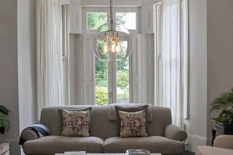Elegant living room featuring a contemporary chandelier with exposed bulbs, surrounded by large wind.