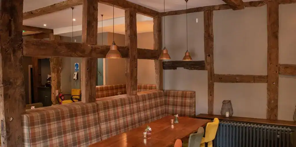 Elegant interior with exposed wooden beams and cozy lighting at Fritz Fryer Lighting UK.
