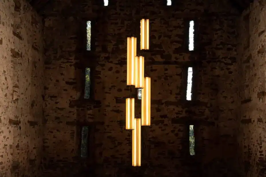 Modern vertical LED light fixture in a brick-walled interior.