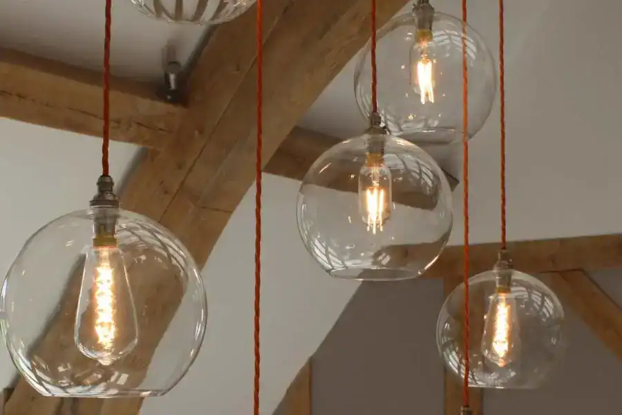 Pendant lights with clear glass globes and Edison bulbs hanging from red cords.