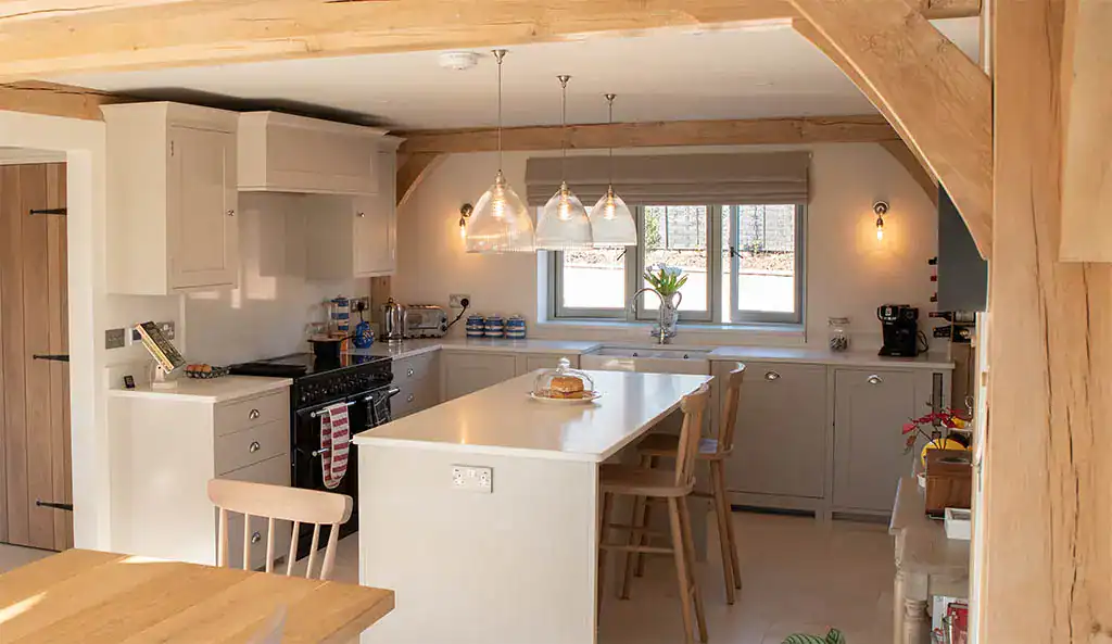 Modern kitchen with wooden accents and stylish lighting fixtures, featuring a central island, white.